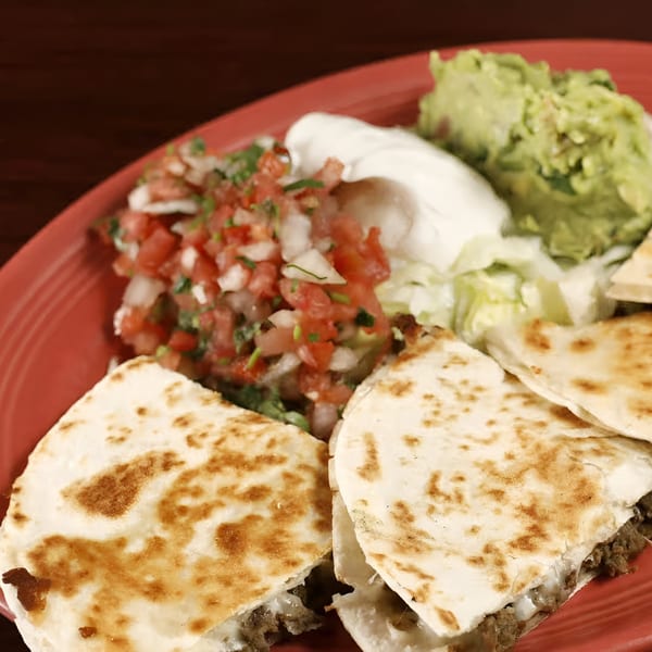 Sancho's Taqueria quesadillas with guacamole, sour cream, pico de gallo, and lettuce on a red plate.