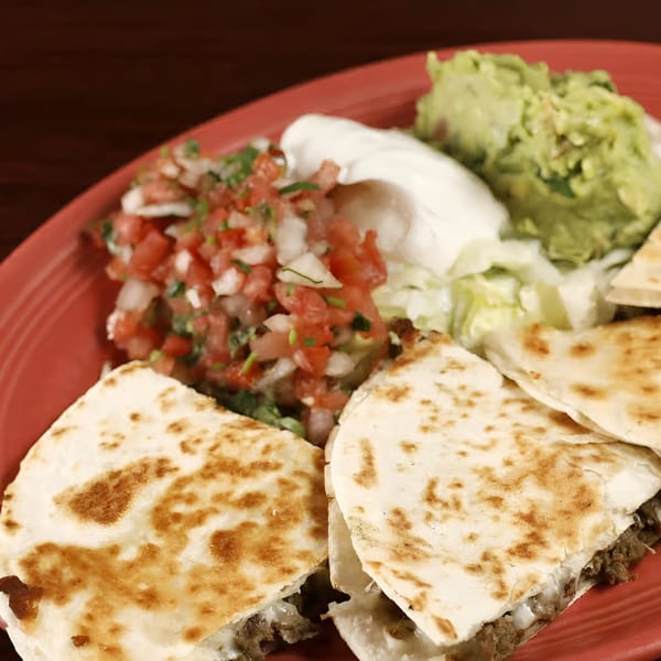 Sancho's Taqueria quesadillas with pico de gallo, guacamole, and sour cream on a red plate.