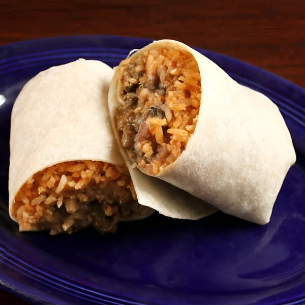 Two Sancho's Taqueria burritos, filled with rice and meat, on a blue plate.
