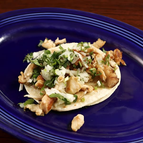 Sancho's Taqueria chicken taco on a blue plate, topped with cilantro and diced onions.